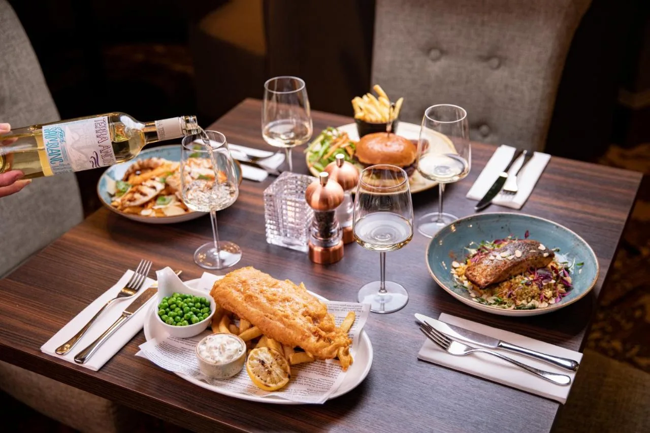 a table with plates of food and glasses of wine at The Station Hotel in Aberdeen